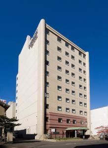 um alto edifício branco com um céu azul em Kitami Pierson Hotel em Kitami