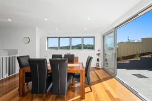 a dining room with a wooden table and black chairs at Brand new house, amazing views, walk to the beach! in Kiama