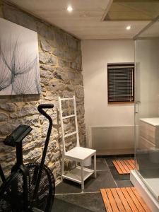 un vélo garé à côté d'un mur en pierre avec une chaise dans l'établissement La LAITERIE Ecaussinnes, à Les Croisettes