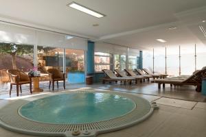 a hot tub in a room with chairs and tables at Hotel Mariant Park in Sa Coma