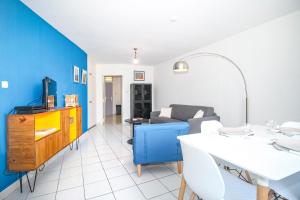 uma sala de estar com uma mesa branca e uma parede azul em L Art est Union - joli T1 à 5min à pied de la plage de Boucan Canot em Saint-Gilles-les-Bains