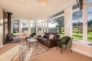 sala de estar con sofá, sillas y ventanas en Easter Kincaple Farmhouse, Sleeps 16, St Andrews, en St Andrews