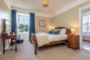 a bedroom with a bed and a desk and windows at Easter Kincaple Farmhouse, Sleeps 16, St Andrews in St. Andrews