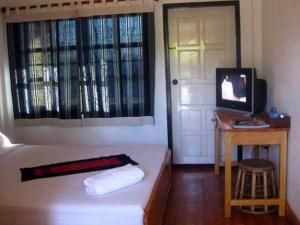 a room with a bed and a television and a door at The Hillside Residence in Muang Phônsavan