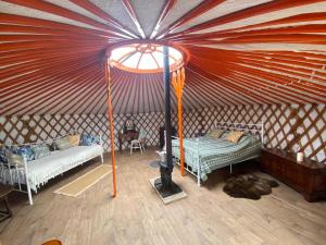a room with two beds and a stove in a yurt at Beautiful Rural Yurt with Wood Fired hot tub 