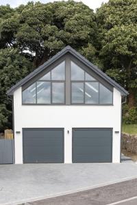 Un garaje blanco con dos puertas de garaje y ventanas. en 1 Bed Studio - Sleeps 4 - Parking - Wifi, en Saint Davids