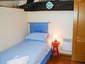 Un pequeño dormitorio con una cama azul y una lámpara en Beautiful 3-Bed Cottage in Passais-Villages, en Saint-Siméon