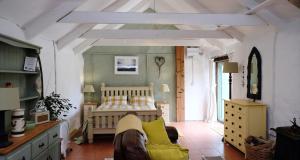 a bedroom with a bed with yellow pillows at Cowshed Cottage located nr Kynance cove in Lizard