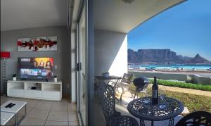 a balcony with a table and chairs and a view of the beach at Sea Spray in Bloubergstrand