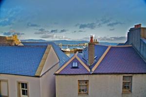 um grupo de telhados de casas com um porto ao fundo em The Royal Hotel em Stromness