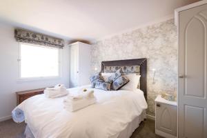 a bedroom with a white bed with towels on it at Deerstalker chalet in Crianlarich