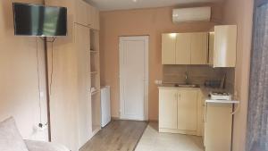 a small kitchen with white cabinets and a television at GuestRoom KOKO in Mtskheta
