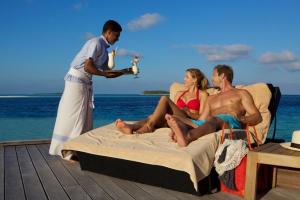 un gruppo di persone seduti su un letto sulla spiaggia di Komandoo Island Resort & Spa a Komandoo