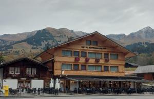 een houten gebouw met tafels en stoelen ervoor bij Hotel Wetterhorn in Grindelwald