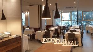 a restaurant with white tables and chairs and windows at AmbientHotels Panoramic in Rimini