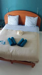 Una cama con dos almohadas azules y un sombrero. en 3 chambres privées dans un jardin d'hiver, garage voiture, vélos, motos, en Tourville-sur-Arques