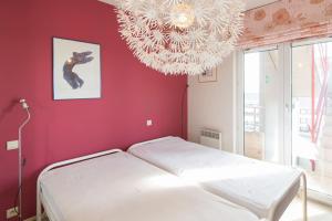 una camera con letto bianco e lampadario pendente di Zongericht appartement met zicht op de jachthaven a Ostenda