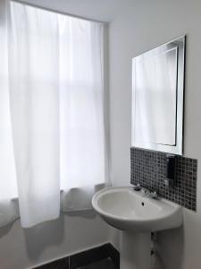 a white bathroom with a sink and a mirror at The Bank in Barking