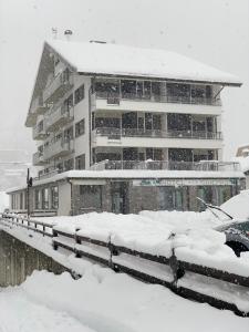 a snow covered building with a car parked in front of it at Hotel Ginepro in Aprica