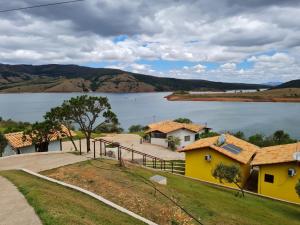 a view of a lake with a yellow house at Pousada Enseada da Ilha in Capitólio