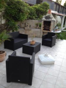 un patio con muebles negros y chimenea en Studio avec piscine privee jardin clos et wifi a Saint Jean d'Angely, en Saint-Jean-dʼAngély