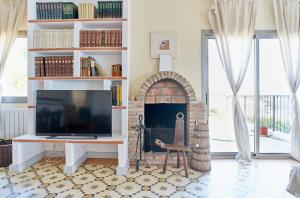 ein Wohnzimmer mit einem Kamin und einem TV in der Unterkunft 6 bedrooms villa with sea view private pool and jacuzzi at Olivella in Olivella