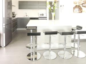 eine Küche mit einer weißen Theke und schwarzen Hockern in der Unterkunft Appartement spacieux à Canet-en-Roussillon 122m² avec vue sur la mer in Canet-en-Roussillon + 40 Fotos