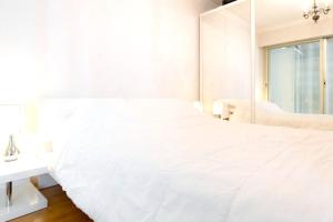 ein weißes Schlafzimmer mit einem großen weißen Bett und einem Spiegel in der Unterkunft Appartement d'une chambre a Cannes a 250 m de la plage avec vue sur la ville balcon amenage et wifi in Cannes