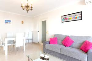 ein Wohnzimmer mit einem grauen Sofa und rosa Kissen in der Unterkunft Appartement d'une chambre a Cannes a 250 m de la plage avec vue sur la ville balcon amenage et wifi in Cannes