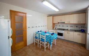 a kitchen with a table with chairs and a refrigerator at 3 bedrooms house with balcony at Teo in Rua De Francos