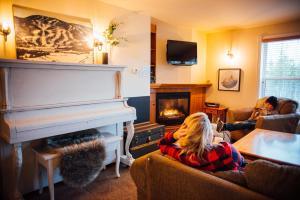 a woman sitting on a couch in a living room with a piano at Maison de Vébron in LʼAnse-Saint-Jean