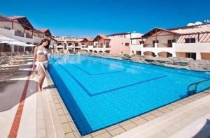 a woman standing next to a swimming pool at 2 bedrooms apartement with shared pool furnished terrace and wifi at Larnaca 2 km away from the beach in Tersephanou