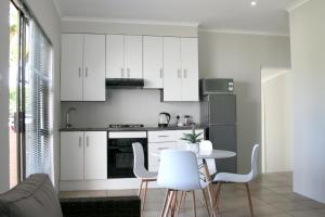 Una cocina con gabinetes blancos y una mesa y sillas. en Summit Place, en East London
