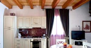 una cucina con armadi bianchi, tavolo e televisore di One bedroom apartement with shared pool furnished balcony and wifi at Partinico 6 km away from the beach a Partinico