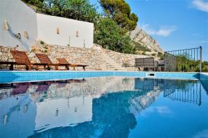 a swimming pool with two chairs next to a building at Elegant villa in Podgora with private pool and sea view in Podgora