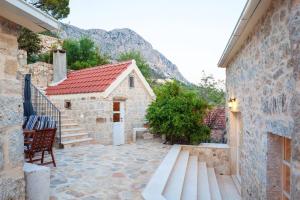 a stone house with a bench next to a building at Elegant villa in Podgora with private pool and sea view in Podgora