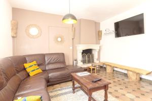 a living room with a brown leather couch and a table at Villa raffinée à Foix avec piscine privée et jacuzzi in Foix