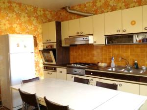 a kitchen with a table and a white refrigerator at Villa raffinée à Foix avec piscine privée et jacuzzi in Foix