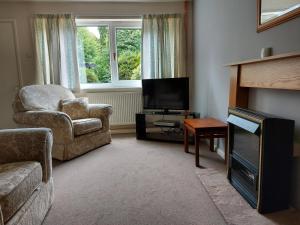 sala de estar con sillón y TV en Canalside village house in Northampton England, en Blisworth