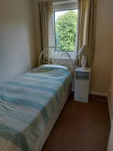 um pequeno quarto com uma cama e uma janela em Canalside village house in Northampton England em Blisworth