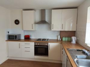 a kitchen with white cabinets and a stove top oven at 3-Bed Cottage Sleeps 4 20 mins to Northampton in Blisworth