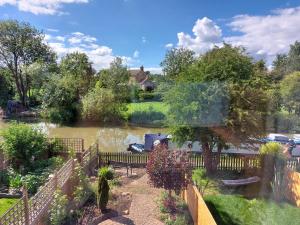 a view of a river with a fence and a house at Canalside village house in Northampton England in Blisworth