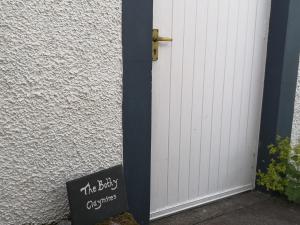 een bord naast een witte deur bij Private Cottage Bothy near Loch Lomond & Stirling in Buchlyvie