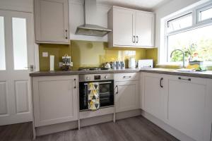 uma cozinha com armários brancos e um forno com placa de fogão em The View 3-Bed Cottage Findochty Buckie Moray em Findochty