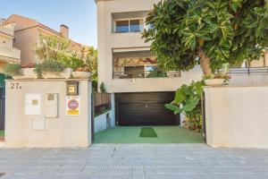 a building with a garage door and a tree at Modern villa with pool in Torredembarra - Sea view in Torredembarra