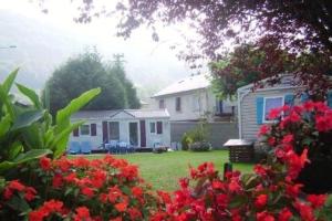 ein kleines Haus mit roten Blumen im Hof in der Unterkunft Charmant Bungalow à Juncalas avec Terrasse et Vue Montagne in Juncalas