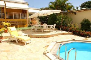a patio with a table and chairs next to a pool at Villa élégante à Sainte-Anne avec piscine privée ouverte toute l'année in Sainte-Anne