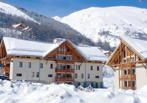 un edificio en la nieve con montañas en el fondo en Studio avec balcon amenage a Valloire a 1 km des pistes, en Valloire