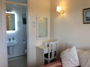 a bathroom with a bed and a sink and a bed and a desk at Hazelbrook Self Catering - Maximum 6 persons in Westport