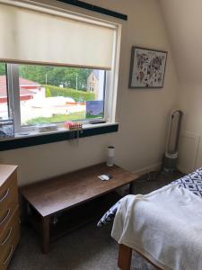 ein Schlafzimmer mit einem Fenster und einer Holzbank neben einem Bett in der Unterkunft Limegrove Comfortable three bedroom house in Law